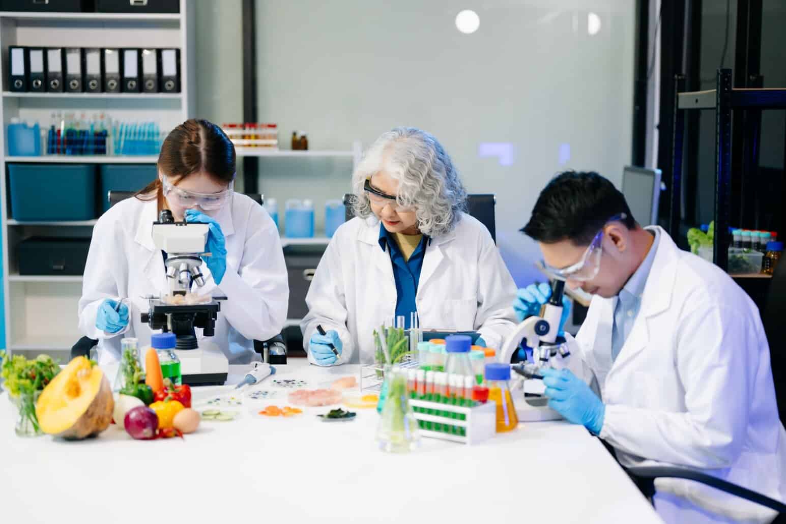 NutriFusion Food scientists in a laboratory analyzing fruits and vegetables using microscopes and test samples.