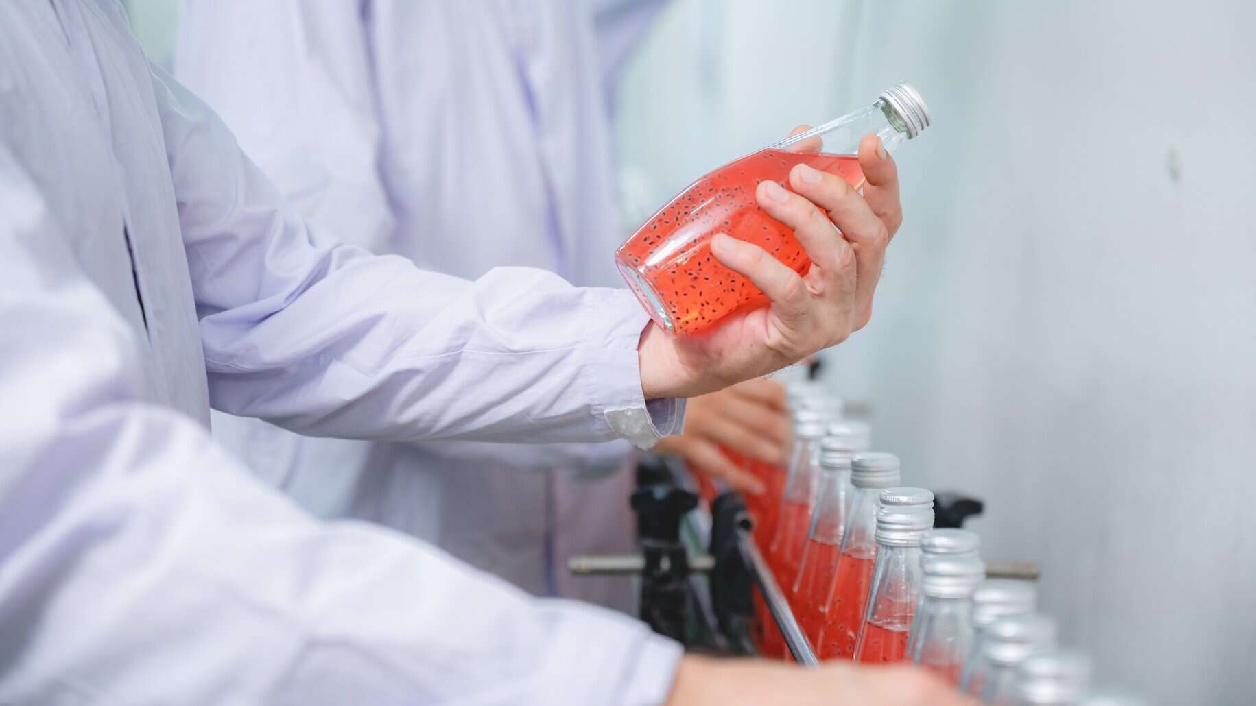 A hand holding a bottle of red beverage made with NutriFusion blend.