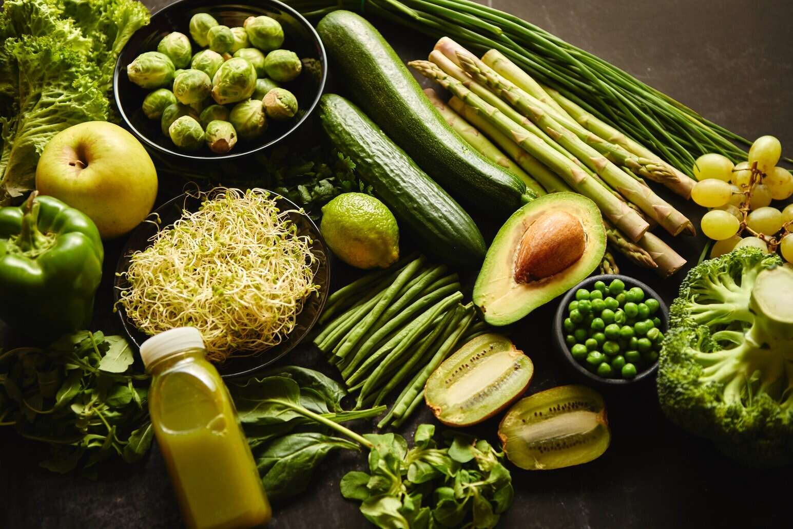 NutriFusion Whole30 ingredients spread with avocado, asparagus, sprouts, and greens on a dark surface.