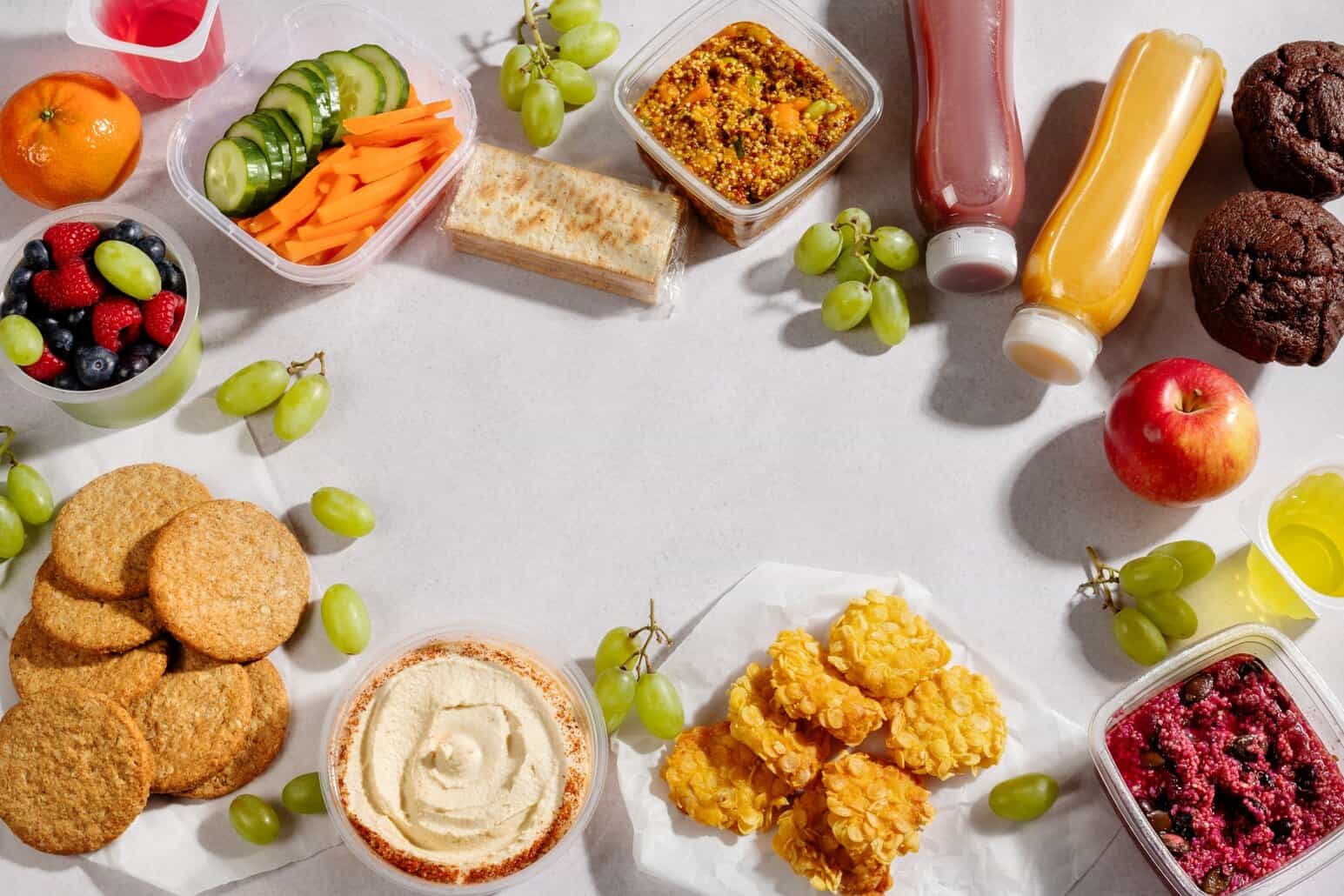 NutriFusion Whole30-style snack spread with grapes, veggie sticks, dips, and juices on a light surface.