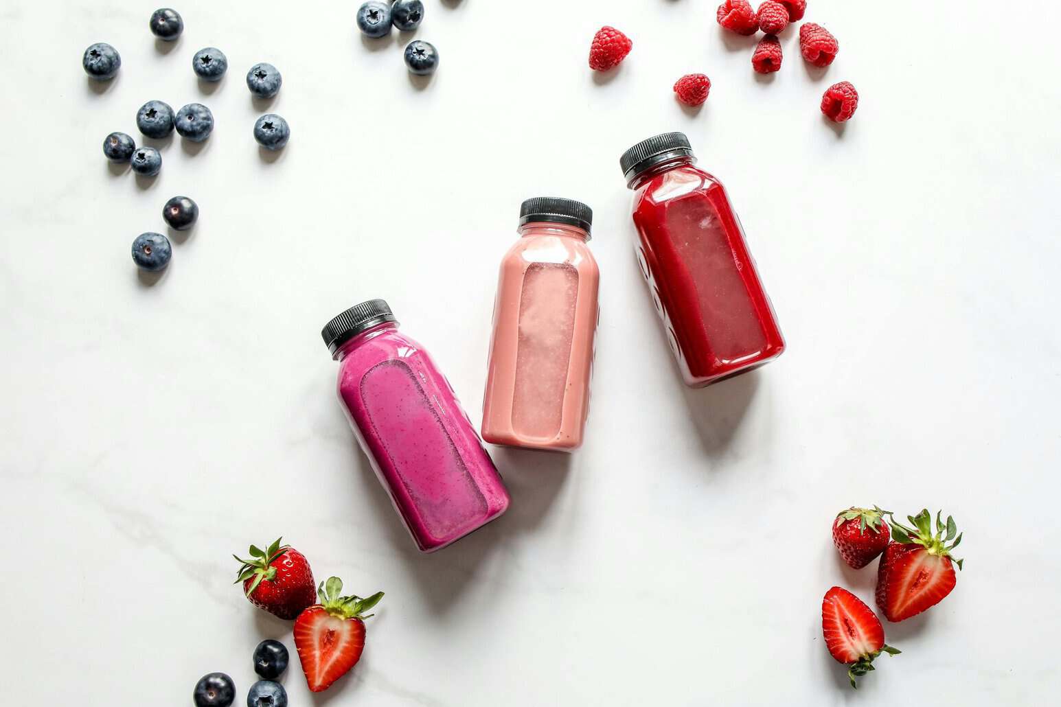 This photo features probiotic drinks laid out on a table with fruits